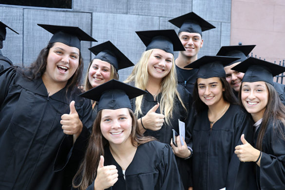 Students at investiture smiling and giving the thumbs up sign.