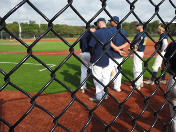 Males standing on the baseball field.