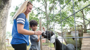 SJC student Valarie Lanzarone helps children feed goats.