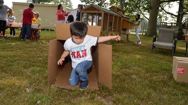 A boy enjoying the simple task of playing with a cardboard box.