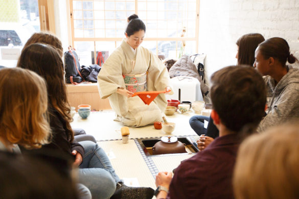 Japanese woman preparing tea, seated with students.