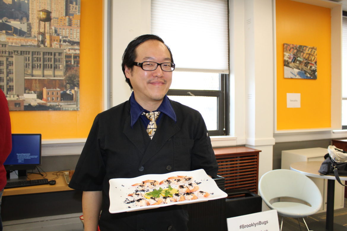 Joseph Yoon holding up his shrimp and black ants dish.