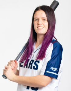 Softball player standing with a bat.