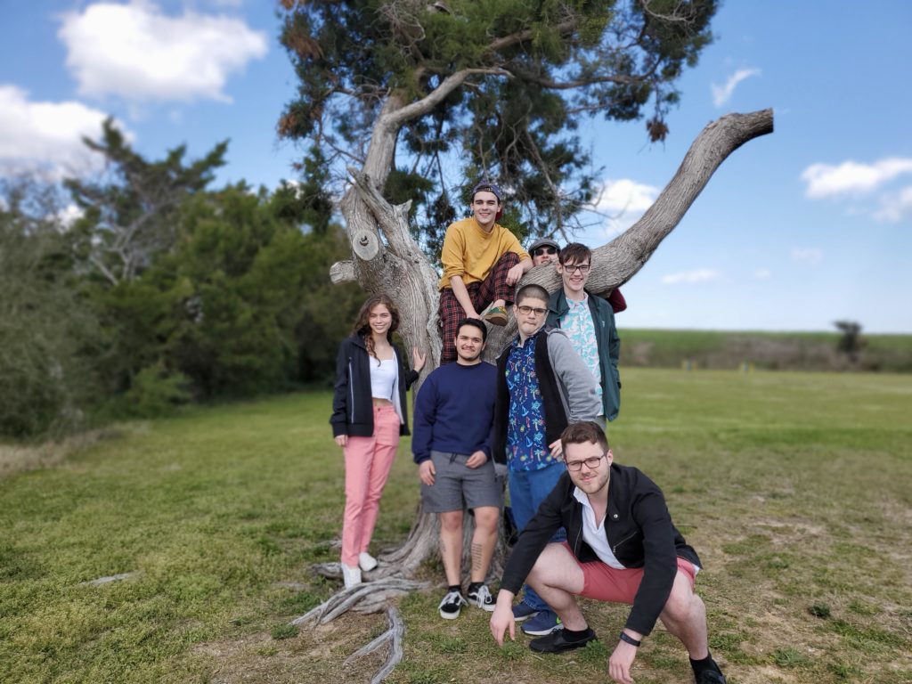 SJC Long Island and Brooklyn students posing in front of a tree in Kure Beach between service efforts during Alternative Spring Break.