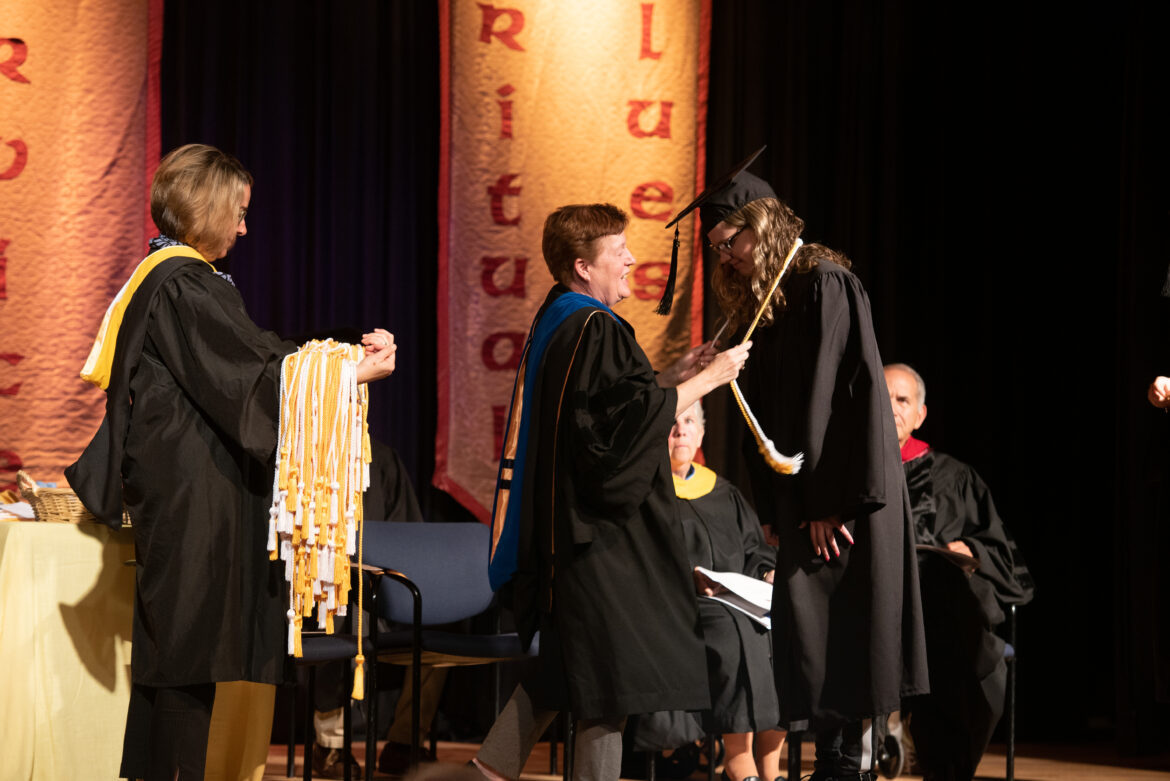 Student with honors receives gold and white cords.