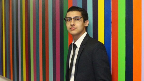 Student standing in front of colorful wall.