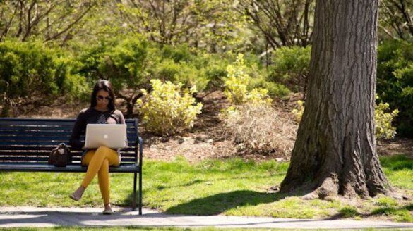 Woman seated on bench with laptop.