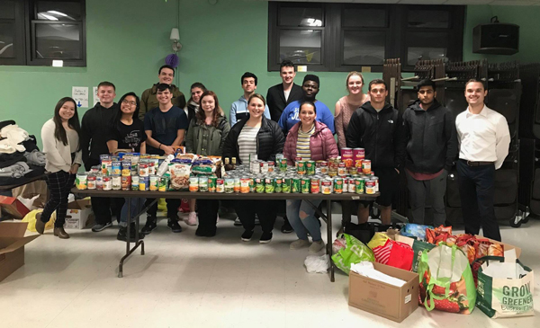Cristian Murphy and SJC Long Island students with food collected during one of the College's past Thanksgiving Food Drives. 