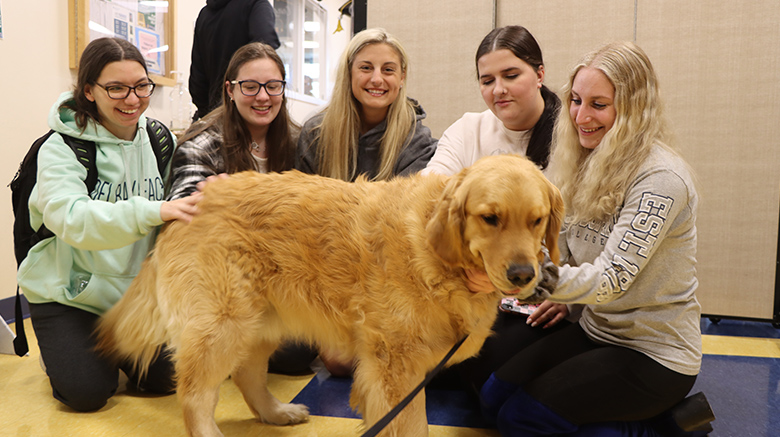 Students petting a dog before finals.
