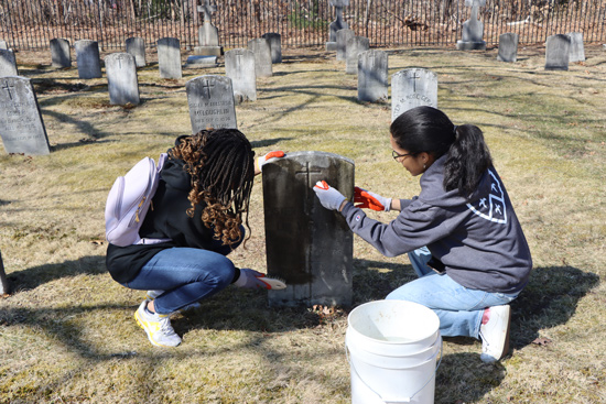 Brutus and a classmate cleaning tombstones at the Sisters of St. Joseph property in Brentwood as part of Campus Ministry's Mission Day.