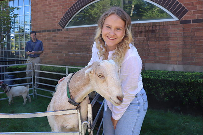 Student posing with a goat.