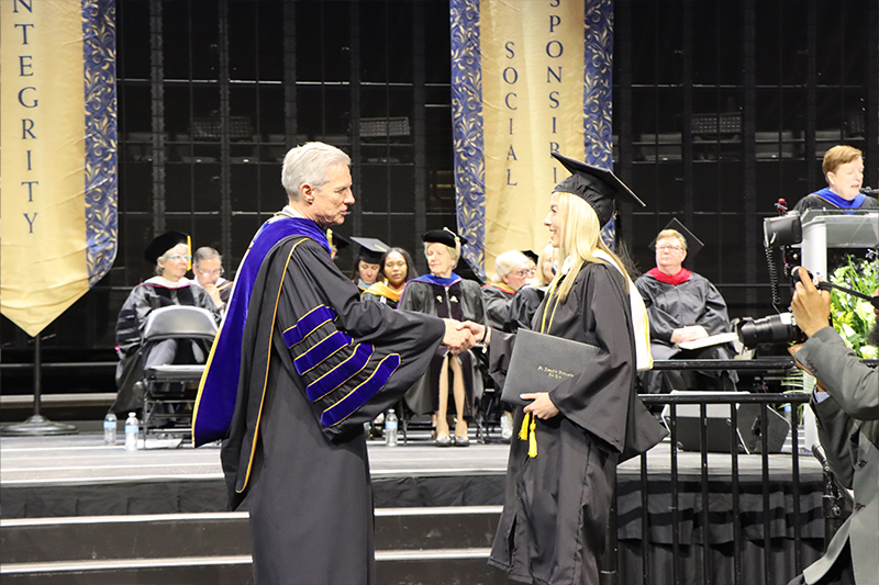 President Boomgaarden shaking a student's hand after they received their diploma.