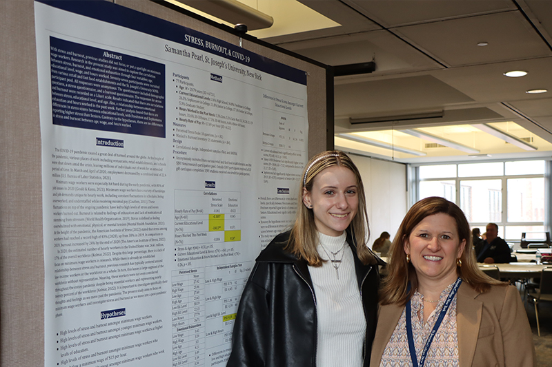 Student with faculty adviser in front of her research.