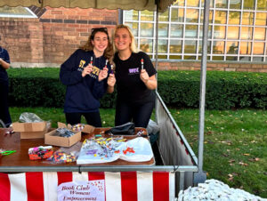 Two members of the women's book club smiling in a booth outside 