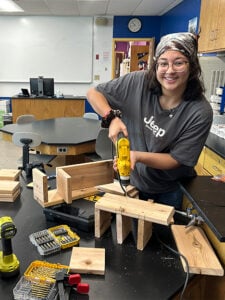 Student working in a workshop as she creates a bee hotel.
